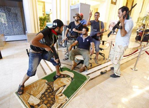 A rebel steps on a poster of Libya's leader Muammar Gaddafi at Rixos hotel, after gunmen released foreigners, in Tripoli August 24, 2011.