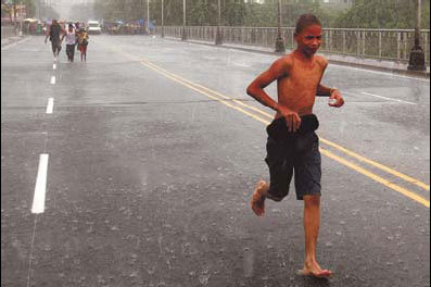 A boy runs along the Sanchez Bridge over the Nigua River in San Cristobal, south of Santo Domingo, on Wednesday as winds and rain from Hurricane Irene pound the island of Hispaniola. The rain is causing rivers to overflow, and at least one woman has died in the flooding. [China Daily]