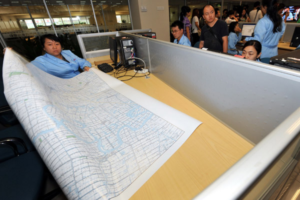 A worker at the National Geomatics Center of China in Beijing shows a map to visitors. China released its first 1:50,000 scale nationwide map on Thursday. [Photo/China Daily] 