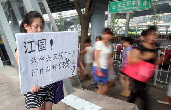 A woman holds up a sign near a subway station on East Third Ring Road in Beijing, Aug 23, 2011, asking her ex-boyfriend to marry her. 