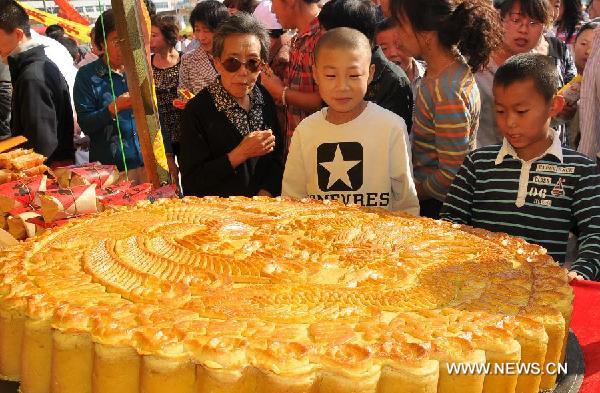 Visitors look at a huge moon cake during a moon cake feast in Shenchi, north China's Shanxi Province, Aug. 23, 2011. 