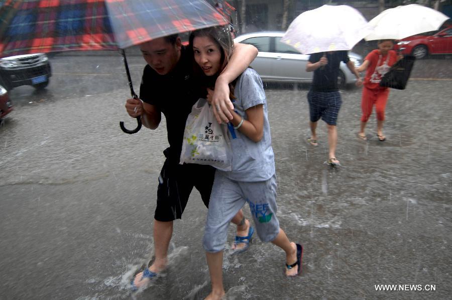 Citizens walk on a waterlogged street in Jinan, capital of east China's Shandong Province, Aug. 27, 2011. A heavy rainstorm hit Jinan on Saturday. [Guo Xulei/Xinhua]