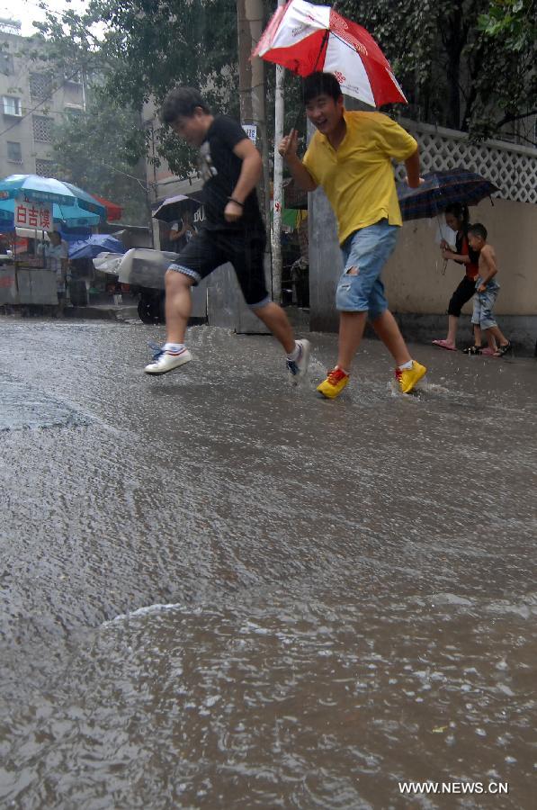 Citizens walk on a waterlogged street in Jinan, capital of east China's Shandong Province, Aug. 27, 2011. A heavy rainstorm hit Jinan on Saturday. [Guo Xulei/Xinhua]