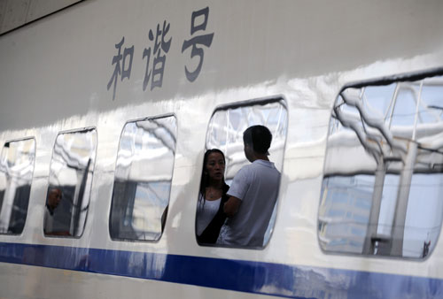 A couple are reflected from a window of a bullet train at Taiyuan Railway Station in Taiyuan, north China's Shanxi Province, Aug. 28, 2011. China started to implement a new operation plan for all bullet trains across the country on Sunday, rescheduling trains to run at slower speeds over safety concerns. [Yan Yan/Xinhua]