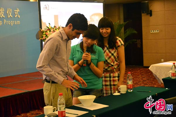The Fujian team invite an American student to participate in a Chinese dice game during their trip presentation in Beijing on Aug. 27, 2011. [Corey Cooper/China.org.cn]