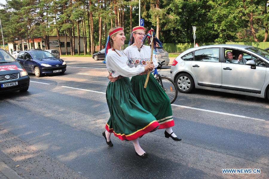 Estonian amateur folk dancers in folk costumes dance while walking on a road on the outskirts of Talinn, capital of Estonia, Aug. 28, 2011. About 7,000 amateur folk dancers took park in the eight-day-and-night 1,000-km marathon dance in Estonia that ended on Sunday. [Xinhua/Victor]