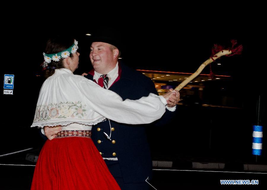 Estonian amateur folk dancers in folk costumes dance while walking in Narva city, the third largest of its kind in Estonia, in the evening of Aug. 22, 2011. About 7,000 amateur folk dancers took park in the eight-day-and-night 1,000-km marathon dance in Estonia that ended on Sunday. [Xinhua/Victor]