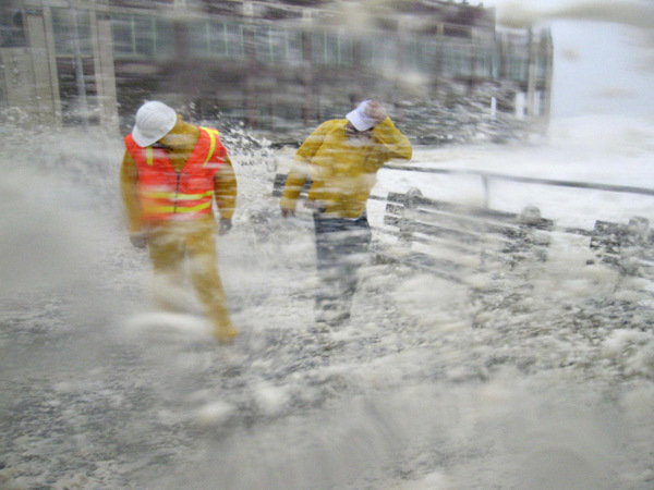 Brian Grant (L) and Bob Bianchini, engineers from the public works department out for a safety inspection, are slammed by waves and storm surge pounding the boardwalk and the beach at first light as Hurricane Irene slams into Asbury Park, New Jersey, August 28, 2011. [China Daily] 