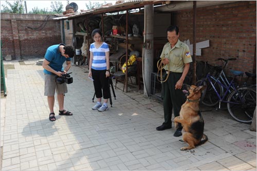 Officer Hao Wuxing demonstrates a police dog's obedience to CRI Video Journalist Jonathan Alpart and Production Assistant Sheng Qianhui at the Beijing Police Dog Camp in Changping on August 19th, 2011. [Photo: CRIENGLISH.com]