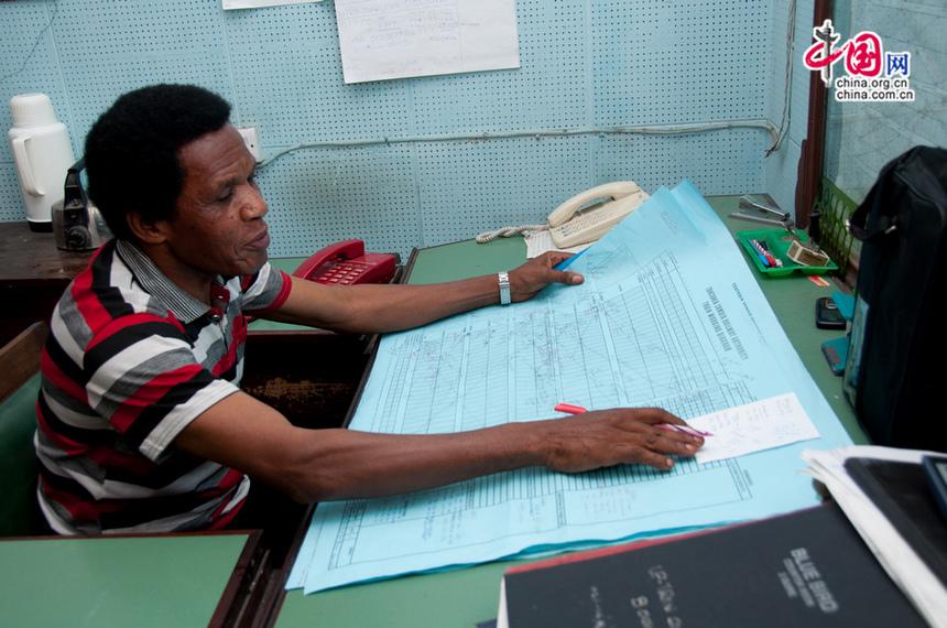 A Tazara official works on the train chart to locate where all the trains are on the tracks. The train chart of the Tazara is still drawn by hand until this day. [Maverick Chen / China.org.cn]