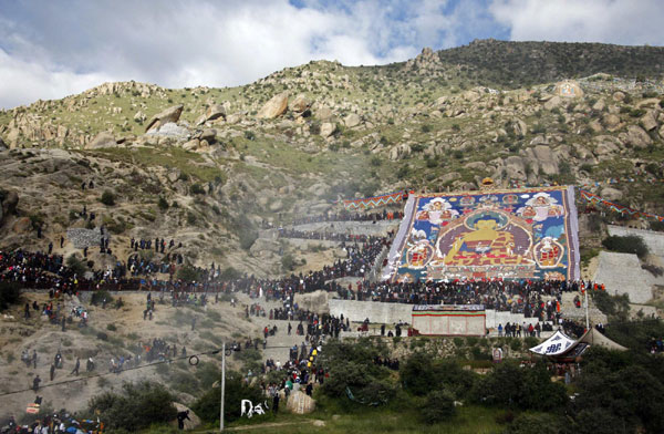 Tibetan Buddhists and tourists view a giant thangka, a religious silk embroidery or painting unique to Tibet, during the Shoton Festival at Drepung Monastery on the outskirts of Lhasa, Tibet autonomous region August 29, 2011.