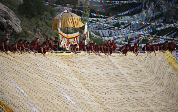 Tibetan monks unfold a giant thangka, a religious silk embroidery or painting unique to Tibet, during the Shoton Festival at Drepung Monastery on the outskirts of Lhasa, August 29, 2011.