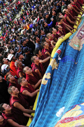 Lamas from Drepung Monastery unfold the huge Thangka painting of Sakyamuni in the unfolding ceremony during the Shoton Festival in Lhasa, Aug 29, 2011. [Photo/Xinhua]