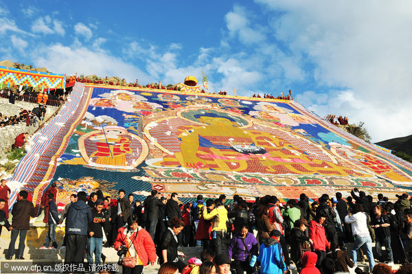 Tourists view a giant thangka, a religious silk embroidery or painting unique to Tibet, during the Shoton Festival at Drepung Monastery on the outskirts of Lhasa, Tibet autonomous region August 29, 2011. [Photo/CFP]