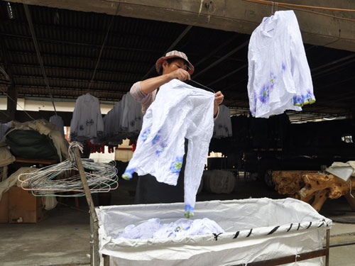 A worker hangs up dyed clothes to dry.[Photo:CRIENGLISH.com] 