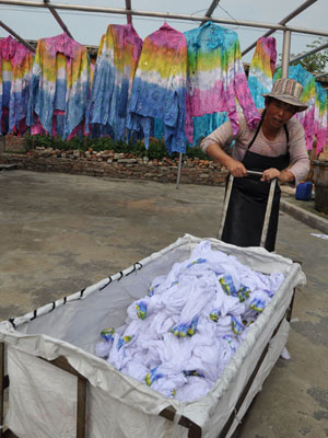 A worker hangs up dyed clothes to dry.[Photo:CRIENGLISH.com]