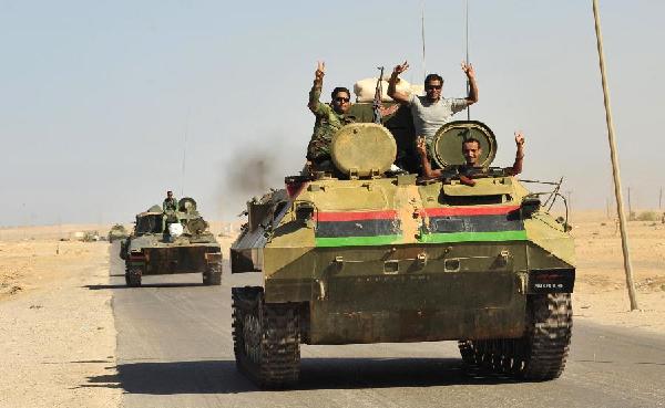 Libyan rebels gesture as they travel on a tank past Bin Jawad while on their way to Muammar Gaddafi's hometown of Sirte August 29, 2011. Libyan forces converged on Gaddafi's hometown of Sirte on Monday, hoping to seal their revolution by seizing the last bastions of a fallen but perhaps still dangerous strongman. [Xinhua] 