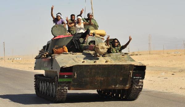 Libyan rebels gesture as they travel on a tank past Bin Jawad while on their way to Muammar Gaddafi's hometown of Sirte August 29, 2011. Libyan forces converged on Gaddafi's hometown of Sirte on Monday, hoping to seal their revolution by seizing the last bastions of a fallen but perhaps still dangerous strongman. [Xinhua] 