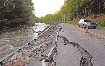 A car passes a section of Route 112 on Monday that was washed out during Hurricane Irene in Halifax, Vermont. [China Daily via agencies] 