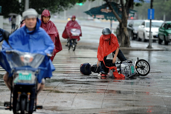 A man falls from his electric bicycle amid rains in Fuzhou, capital city of east China's Fujian Province Aug 31, 2011. Nanmadol landed in the province's Jinjiang city at 2:20 am on Wednesday, packing a wind of 20 meters per second. [Xinhua photo] 