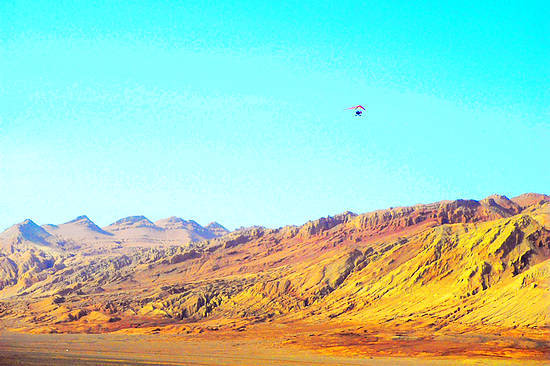 Tourists can take a parasail and have an aerial view of the Flaming Mountain. [Photo: travel.sina.com.cn]