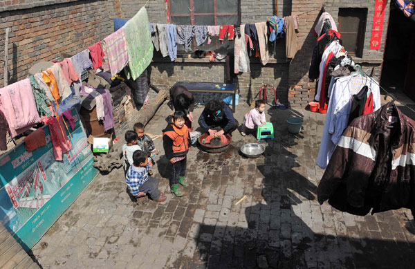 Li washes clothes with some of her children around her, March 19, 2011. [Photo/Xinhua]