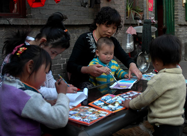 Li teaches children to write at home, April 28, 2011. [Photo/Xinhua] 