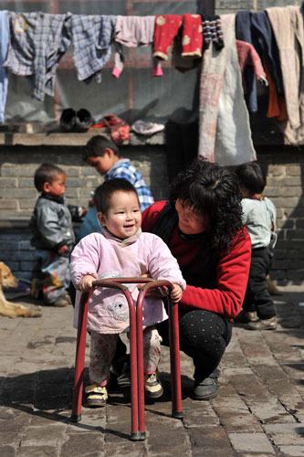 An 11-month-old baby learns to walk under Li's care, March 19, 2011. [Photo/Xinhua]