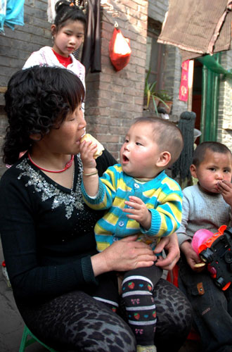 A child in Li's arms shares a snack with her, April 28, 2011. [Photo/Xinhua]
