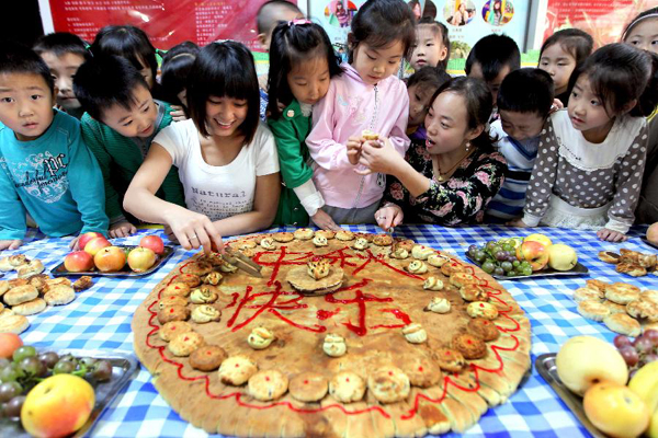 Children and teachers from a kindergarten eat mooncakes made on their own in Yuncheng City, north China's Shanxi Province, Sept. 7, 2011. As the Mid-Autumn Festival is coming, children here made mooncakes to experience the traditional Chinese culture.
