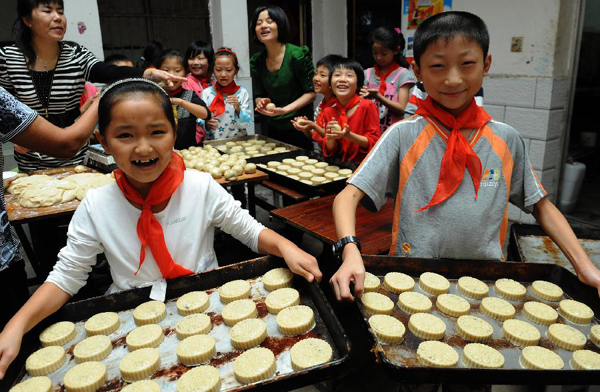 Children of migrant workers from a primary school show the mooncakes they made in Liu'an City, east China's Anhui Province, Sept. 7, 2011. As the Mid-Autumn Festival is coming, children in many kindergartens made mooncakes to experience the traditional Chinese culture. 