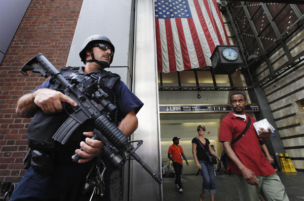 Members of the public react as they walk past a New York Police Department Hercules team on patrol near Penn Station in New York August 24, 2011. [Agencies] 