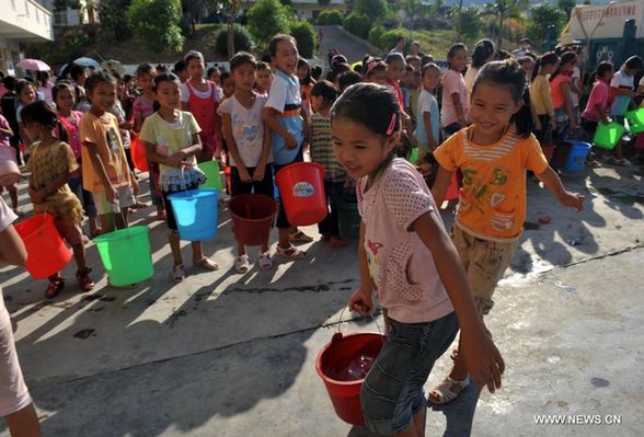 Students of Jiuzhou Township Elementary School get drinking water with barrels in Tianlin County, south China's Guangxi Zhuang Autonomous Region, Sept. 7, 2011. [Xinhua]