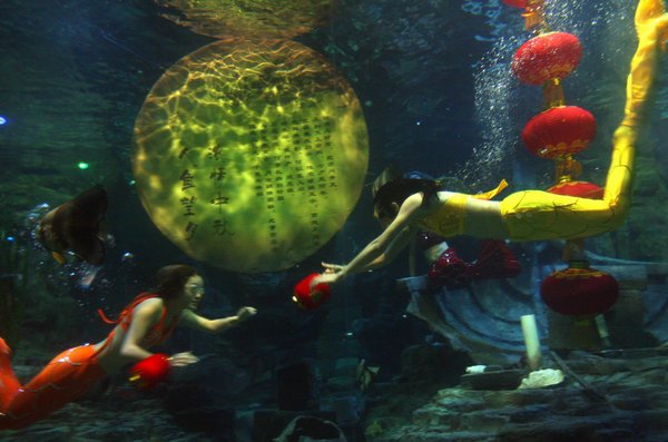 Mermaids swim around the 'full moon' and red lanterns to greet the upcoming Mid-Autumn Festival in Donghu Ocean World of Wuhan, capital of Central China's Hubei province, Sep.9, 2011. [CFP Photo]