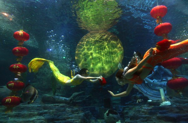 Mermaids swim around the 'full moon' and red lanterns to greet the upcoming Mid-Autumn Festival in Donghu Ocean World of Wuhan, capital of Central China's Hubei province, Sep.9, 2011. [CFP Photo]