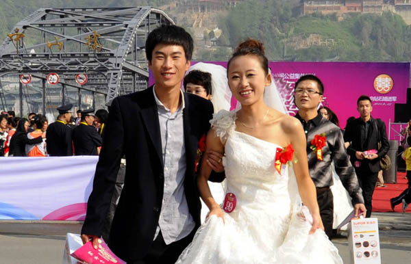 A newlywed couple smiles in Gansu province on Sept 12, 2011. 100 couples tied the knot in a group wedding in Gansu province on Sept 12, this year's Mid-Autumn Festival.[Photo/Xinhua]