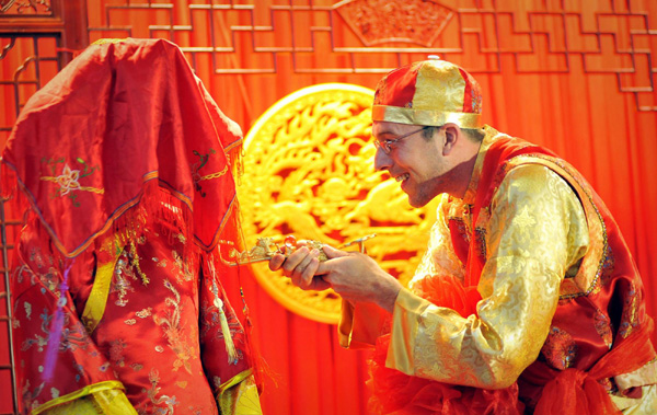 A German groom Simon lifts the veil of Chinese bride Cao Jia in Tianjin on Sept 12, 2011. The couple held a traditional Chinese wedding on the Mid-Autumn Festival in Tianjin, which fell on Sept 12 this year. [Photo/Xinhua] 