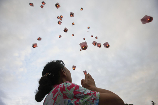 A woman looks on as lanterns ascend in celebration of the Mid-Autumn Festival in northern Taiwan province, Sept 12, 2011. [Photo/Xinhua]