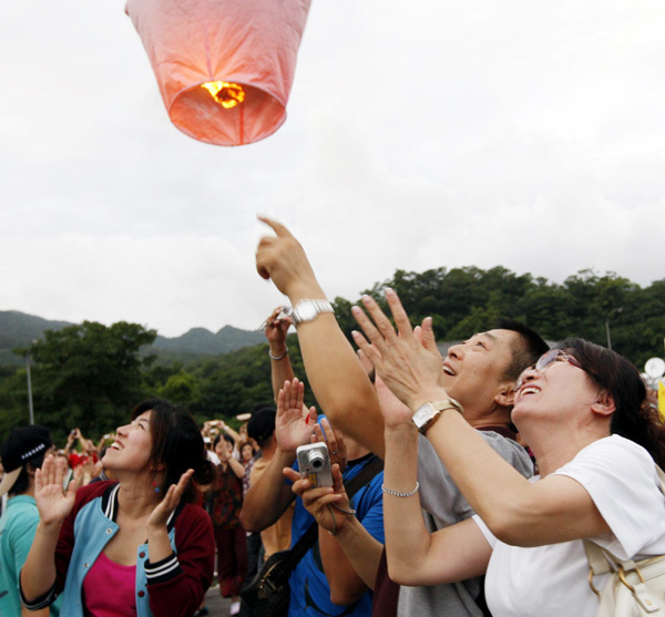 Visitors look on as lanterns ascend in celebration of the Mid-Autumn Festival in northern Taiwan province, Sept 12, 2011. [Photo/Xinhua]