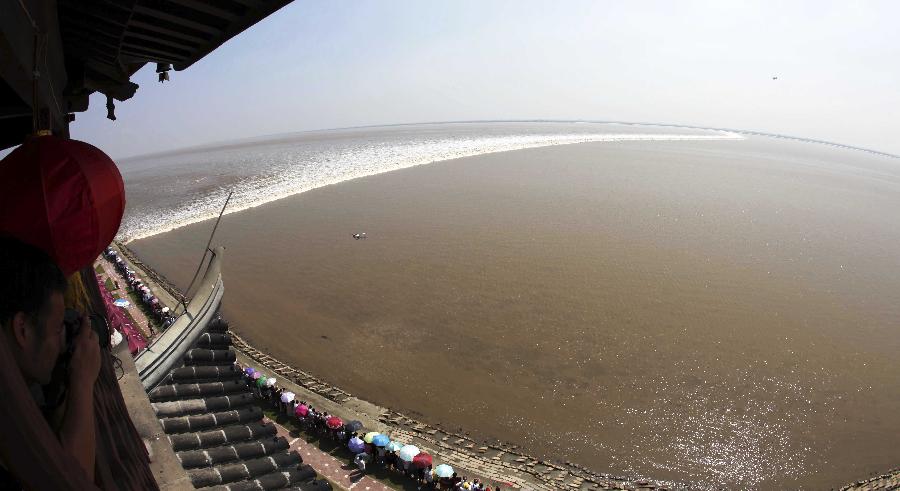 Roaring waves surge forward along the Qiantang River in Jiaxing City, east China's Zhejiang Province, Sept. 13, 2011. Tens of thousands of tourists have gathered in Jiangxing, one of the best tide-watching places, to watch the magnificent tidal bore. The tidal bore, an annual spectacular sight since ancient times, is known in the world for its roaring tides. The natural wonder has become a popular attraction for tourists across the globe. [Xinhua/Shen Da]