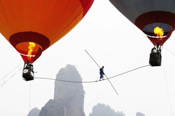 Saimaiti Aishan, the nephew of Adili Wuxor, walks on a tightrope connected between two hot air balloons during an attempt for setting a record in Langshan, Central China's Hunan province, Aug 6, 2011. [Photo/Asianewsphoto]