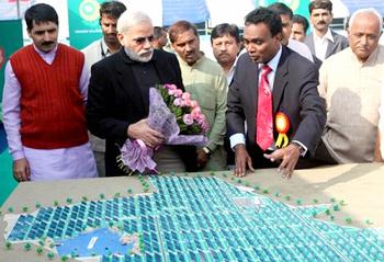Gujarat Chief Minister Narendra Modi, with flowers, at the foundation stone ceremony in Charanka, inspects a model of the project. December 30, 2011. [narendramodi.in] 