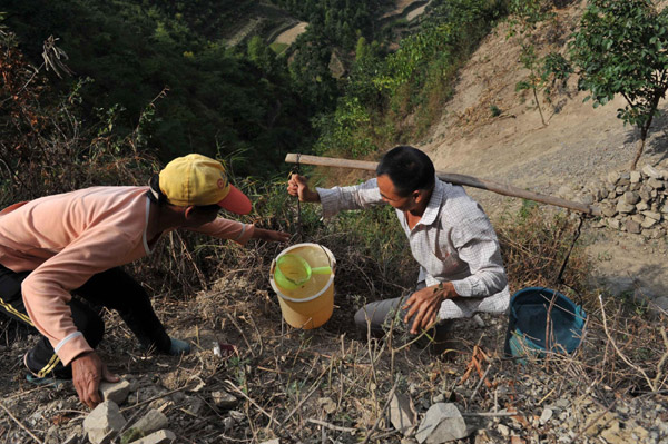 Villagers carry drinking water home in the Nahong neighborhood of Yakou Village, Longlin County in Guangxi Zhuang autonomous region on Sept 15, 2011. 
