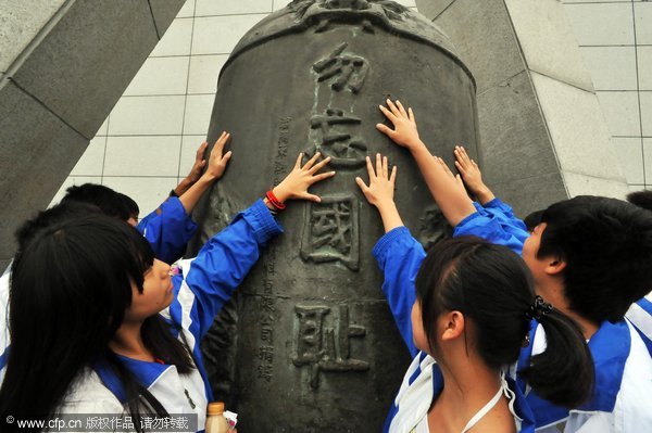 Students touch an alarming bell with 'Do not forget national humiliation' carved on it near the '9.18' Historical Museum in Shenyang, capital of Northeast China's Liaoning province, Sept 17, 2010. [Photo/CFP]