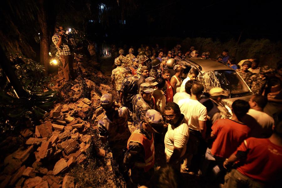 Members of the Nepalese army gather around a damaged car after the wall surrounding the British Embassy collapsed on top of the car that was passing by during the 6.8 magnitude earthquake that struck Kathmandu September 18, 2011. [Xinhua/Reuters Photo]
