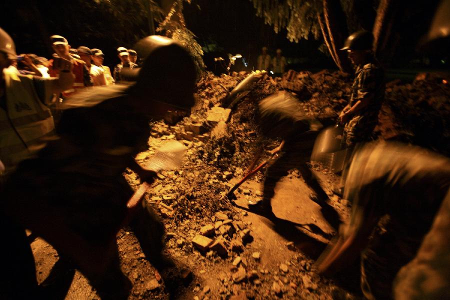 Members of the Nepalese army clear stones around a damaged car after the wall surrounding the British Embassy collapsed on top of the car that was passing by during the 6.8 magnitude earthquake that struck Kathmandu September 18, 2011. [Xinhua/Reuters Photo]