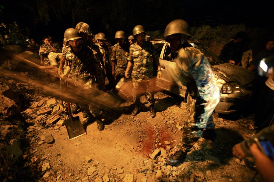 Members of the Nepalese army clear stones around a damaged car after the wall surrounding the British Embassy collapsed on top of the car that was passing by during the 6.8 magnitude earthquake that struck Kathmandu September 18, 2011. [Xinhua/Reuters Photo]