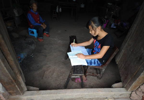 Li does homework on a stool as there is no desk at her home in Ganshui town of Qijiang county, Chongqing municipality on Sept 18, 2011. [Photo/Xinhua]