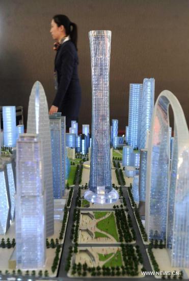 A staff member walks past a building model of the city&apos;s tallest skycraper in Beijing, capital of China, Sept. 19, 2011. Beijing will begin building the city&apos;s tallest skyscraper in its central business district. The 108-story 510-meter building, called &apos;China Zun&apos;, is shaped like a zun, an ancient Chinese wine vessel, and will be completed within five years. [Luo Xiaoguang/Xinhua]