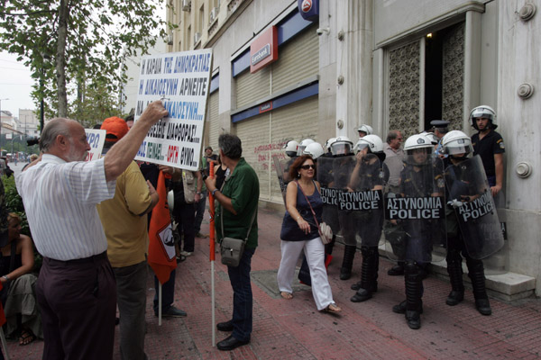 A protester (L) holds a sign during a demonstration in central Athens, capital of Greece, Sept. 20, 2011. Greek public sector workers staged a demonstration on Tuesday protesting against the Greek government's new austerity measures of lay-offs and salary cuts in the public sector. [Xinhua]